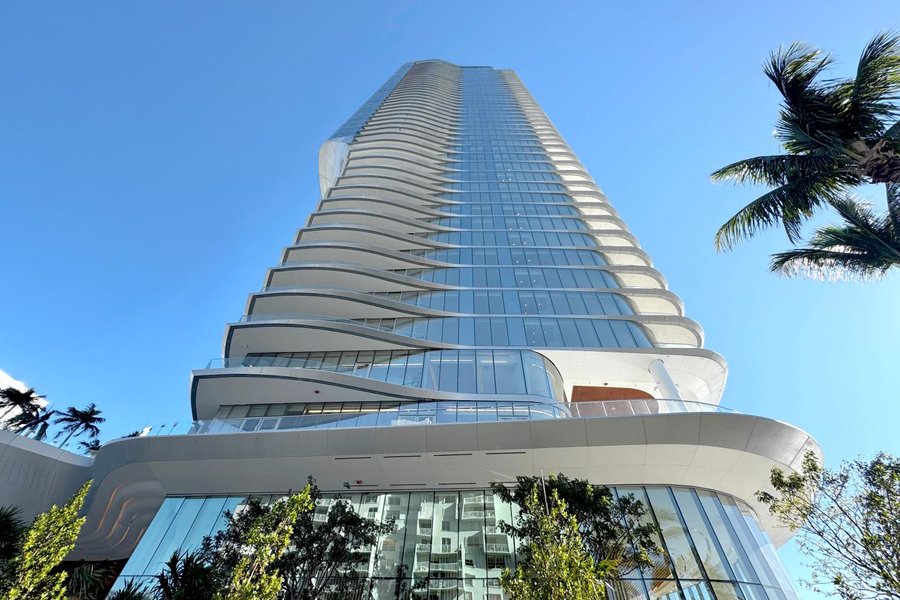 Photo looking up at the curved, sail-like Una Residences tower